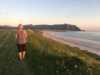 Woman wandering at å long beach at the sunset.