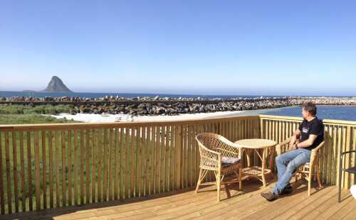 Mann sitter på veranda med utsikt mot Bleiksøya.