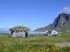 Barbecue hut and mobile home at a campsite with ocean and mountain view.