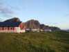 Service building and mobile homes on a field with mountains in the background.