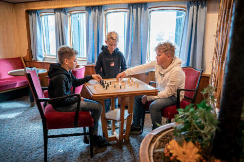 Gutter spiller skakk på MS Finnmarken.