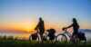 A couple have stopped their bikes to look at the midnight sun.