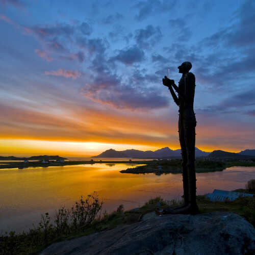 Skulpturen Mannan fra havet, med fjorden og midnattssolen i bakgrunnen.