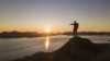 Kenn points at midnight sun from a mountain top